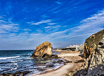 Rock formation on beach against blue sky