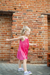 Young woman standing against brick wall