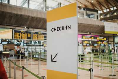 White check in direction board near counters with metal pillars in modern light public airport with flight schedule on contemporary signboards