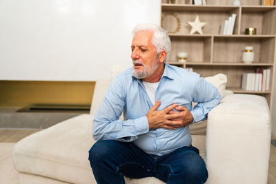 Young man using mobile phone while sitting on sofa at home