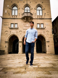 Full length portrait of man standing against building