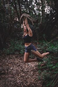 Woman with arms raised on field in forest