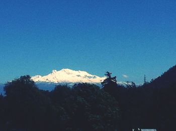 Low angle view of silhouette mountain against clear blue sky