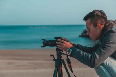 Side view of man photographing at beach