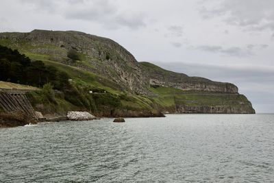 Scenic view of sea by cliff against sky