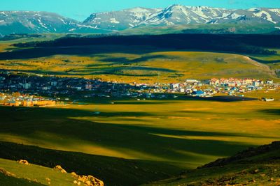 Scenic view of field and buildings against mountains