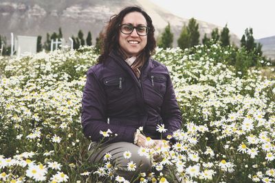 Portrait of smiling woman sitting amidst flowers
