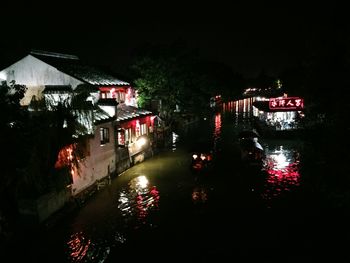 Illuminated buildings by river at night