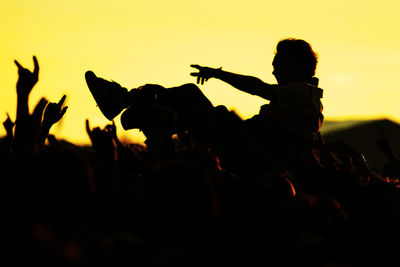 Close-up of silhouette people in concert against sky during sunset