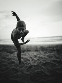 Portrait of shirtless boy screaming while playing at beach against sky