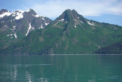 Scenic view of lake by mountains against sky