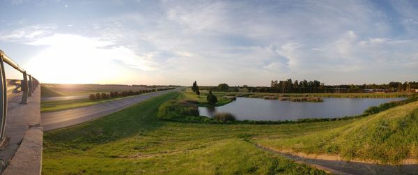 Scenic view of landscape by river against sky
