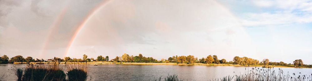 Panoramic view of lake against rainbow in sky