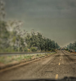 Road by trees against sky seen through windshield