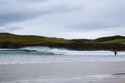 Scenic view of sea against sky and man with surfboard