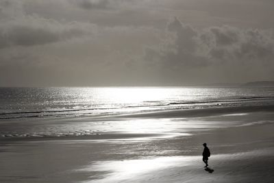 Silhouette man standing on beach against sky during sunset