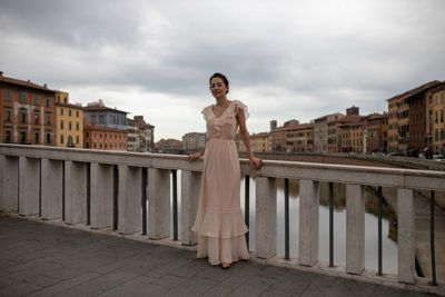 Woman standing by railing against river in city