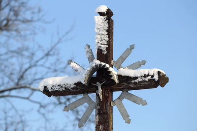 Low angle view of cross on snow against clear sky