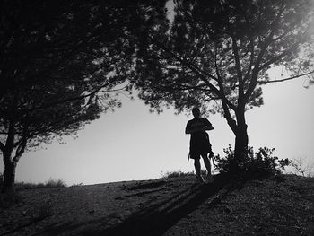 Rear view of man walking on street amidst trees