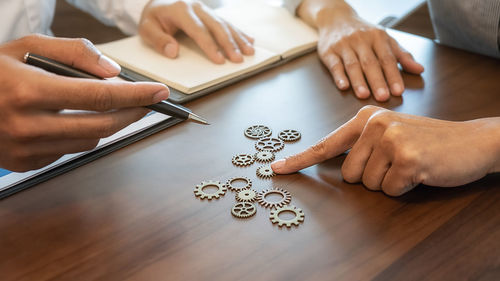 Midsection of business people discussing over gear on table