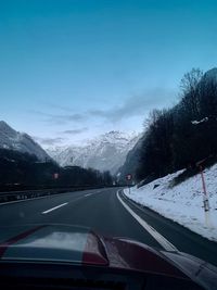 Road against sky seen through car windshield during winter