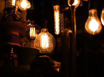 Close-up of illuminated light bulb hanging at night