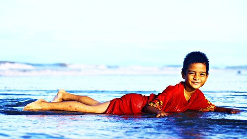 Portrait of smiling boy in sea against sky