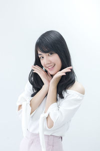 Portrait of smiling young woman against white background