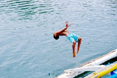 High angle view of boy backflipping in river