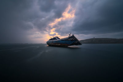 Boat on sea against sky at sunset