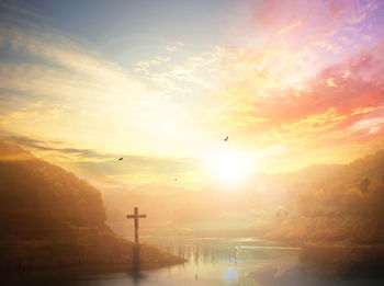 Birds flying over lake against sky during sunset