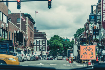 Road sign on city street against sky