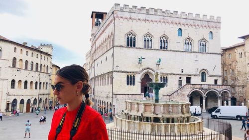 Portrait of woman standing against buildings in city