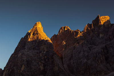 Low angle view of rocky mountains against clear sky