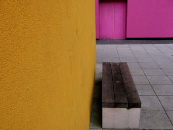 Wooden bench by orange wall on tiled floor