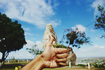 Close-up of person showing thumbs up against sky