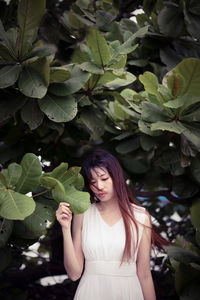 Young woman standing against plants