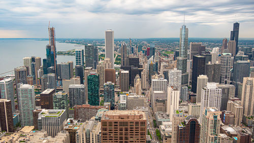 Aerial view of buildings in city against cloudy sky