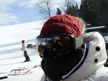 Close-up of person wearing ski goggles and knit hat on snowy field