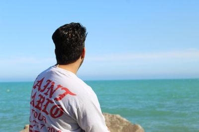Rear view of man looking at sea against sky