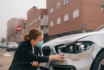 Woman standing by car on city street