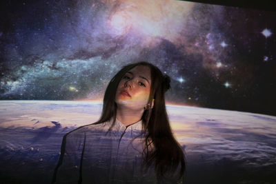 Portrait of young woman against sky at night
