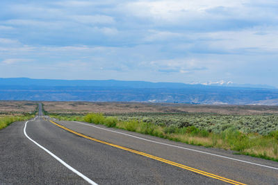 Road passing through land against sky