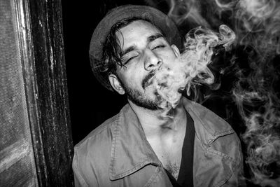 Portrait of man smoking while standing outdoors