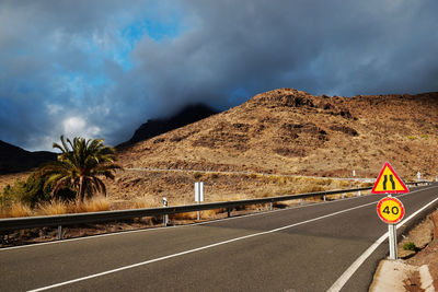 Road by mountain against cloudy sky