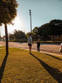 Rear view of people walking on street against sky