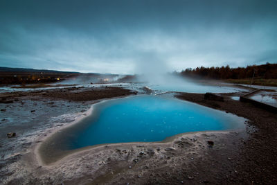 Scenic view of hot springs against cloudy sky