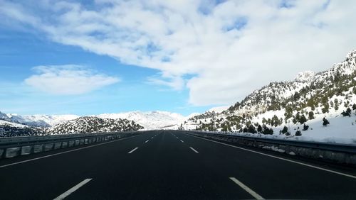 Road amidst snowcapped mountains against sky