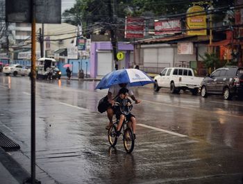 Rear view of man cycling on wet street