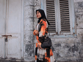 Young-aged woman standing againts abandoned building 